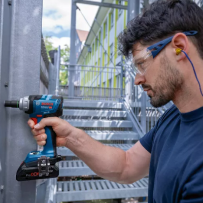 Homem a usar parafusadeira elétrica Bosch em portão metálico