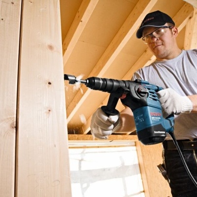 Homem a usar furadeira Bosch numa estrutura de madeira em construção