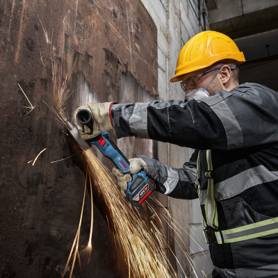 Trabalhador com capacete a usar esmerilhadora num ambiente industrial
