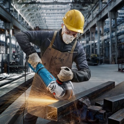 Homem a cortar metal com esmeriladora em oficina industrial
