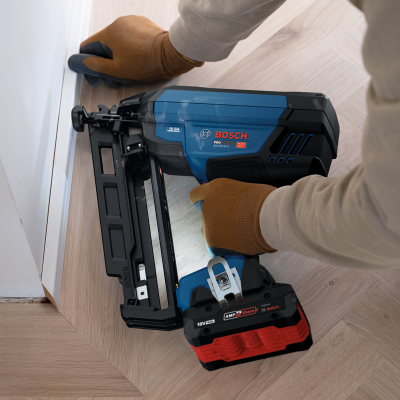 Pistola de pregos a bateria Bosch Pro azul e preta num chão de parquet
