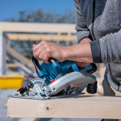 Pessoa a usar serra circular elétrica para cortar madeira num local de construção