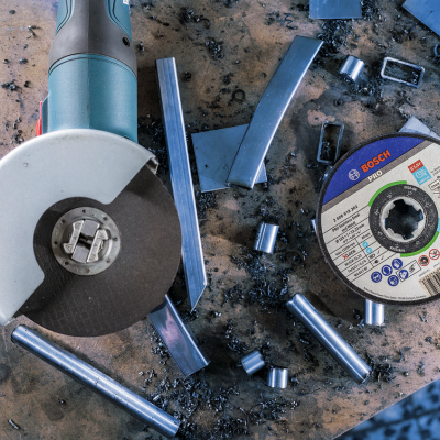 Esmerilhadora elétrica Bosch com disco de corte e disco de corte Bosch sobre mesa de trabalho com pedaços de metal