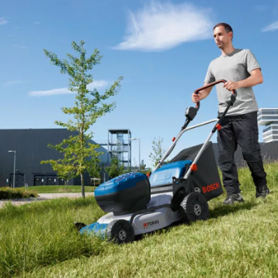 Homem a cortar relva com cortador elétrico Bosch num dia ensolarado