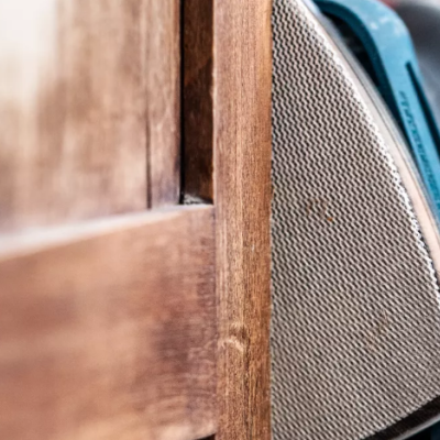 Ferro de engomar azul e cinza sobre madeira com mão com luva cinza