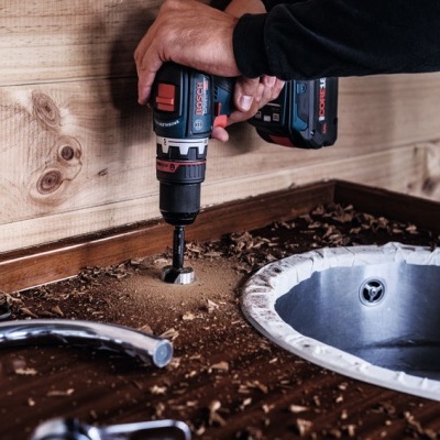 Furadeira Bosch a perfurar madeira junto a pia de metal
