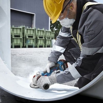 Trabalhador a lixar estrutura metálica branca com lixadora elétrica