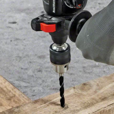 Furadeira elétrica a furar madeira com mão enluvada