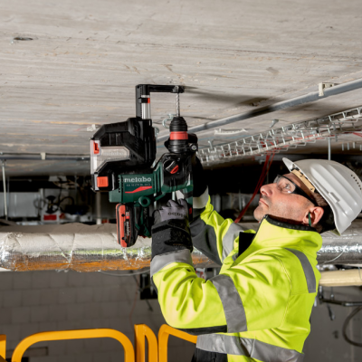 Homem a usar furadora Metabo em teto de espaço industrial