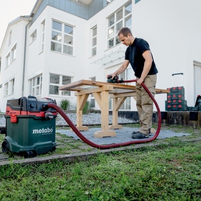 Homem a usar aspirador Metabo em máquina de carpintaria ao ar livre