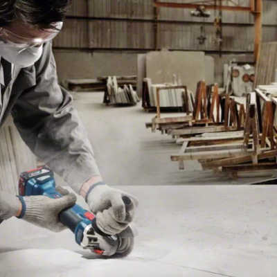 Pessoa a usar esmerilhadora elétrica Bosch numa superfície branca num espaço industrial