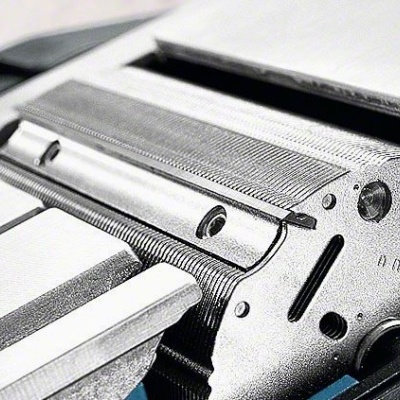 Detalhe de máquina de escrever antiga metálica cinza e azul com texto gravado 'n max'