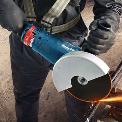 Pessoa utilizando serra elétrica azul para cortar metal numa morsa