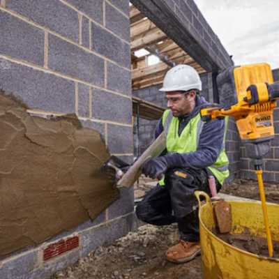 Homem aplicando argamassa em muro de blocos de cimento em construção