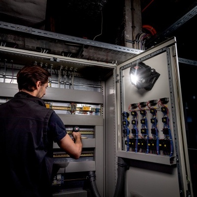 painel elétrico industrial aberto com componentes e homem a trabalhar