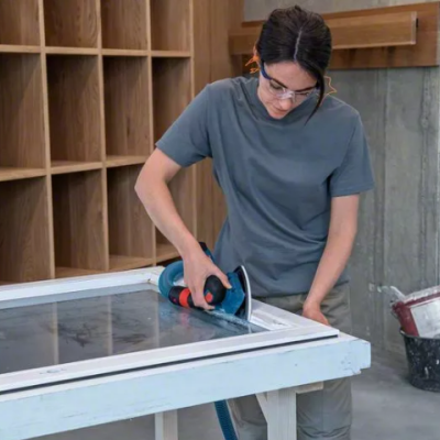 Mulher a cortar vidro com ferramenta elétrica num espaço interior