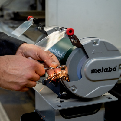 Amoladora de bancada Metabo cinzenta a ser usada num ambiente industrial