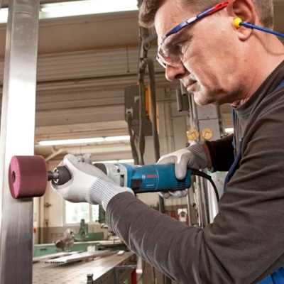 Homem a polir superfície metálica com ferramenta elétrica num ambiente industrial