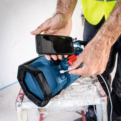 Coluna portátil azul e preta com smartphone a carregar