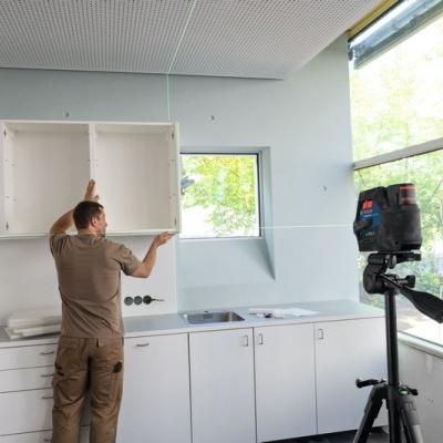 Instalação de armário de cozinha branco em ambiente interior com janela grande e equipamento de medição