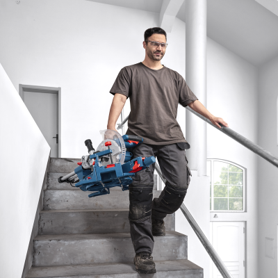Homem com serra de corte azul a descer escadas interiores
