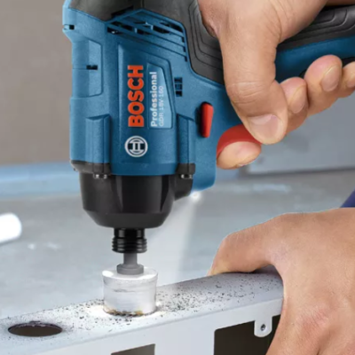 Furadeira Bosch azul a perfurar uma placa metálica com mãos a segurar