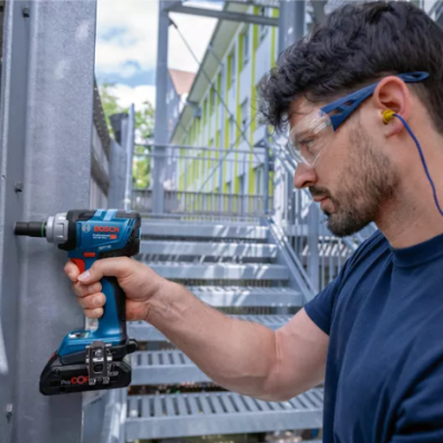 Parafusadeira Bosch azul e preta com homem a usar equipamento de proteção