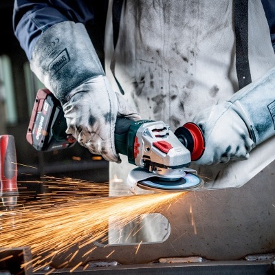 Pessoa a usar esmeriladora elétrica num ambiente de oficina