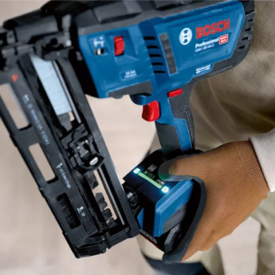 Pistola de pregos Bosch azul e preta segurada por mão com luva castanha