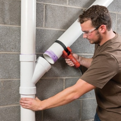 Homem a trabalhar em tubos de PVC branco num ambiente de construção