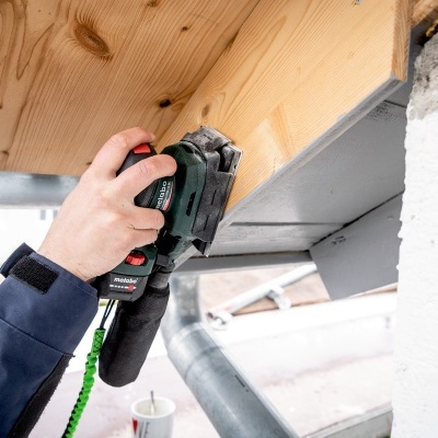 Pessoa a usar ferramenta elétrica para lixar madeira exterior