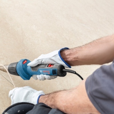 Trabalhador com luvas a usar pistola de ar quente em tubo plástico