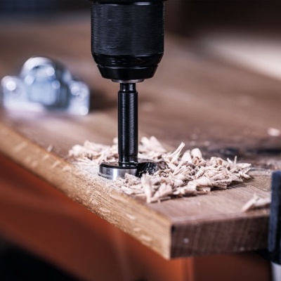 Furadeira elétrica perfurando madeira numa bancada de carpintaria