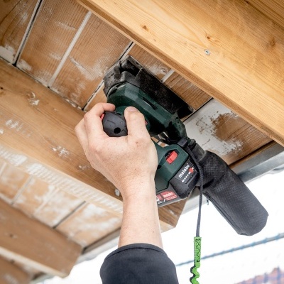 Pessoa a usar lixadora elétrica num teto de madeira