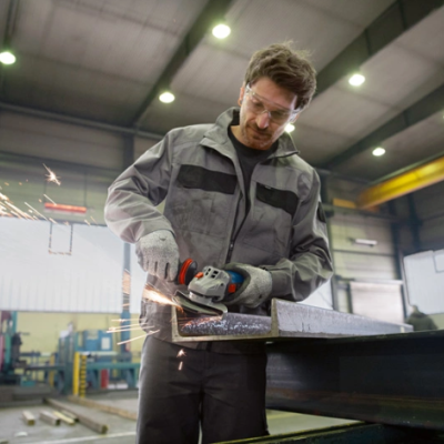 Homem em oficina usando rebarbadora elétrica para cortar metal com faíscas