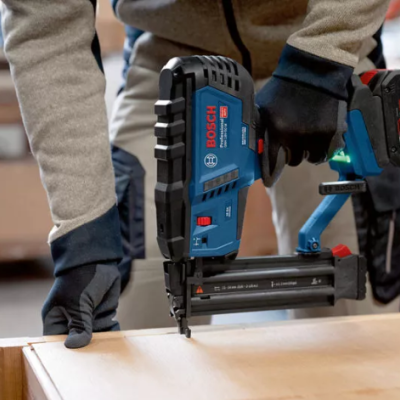 Pistola de pregos elétrica Bosch Professional azul e preta em uso numa superfície de madeira