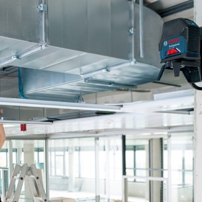 Aparelho laser Bosch GLL 3-80 CG fixado numa parede em espaço comercial moderno