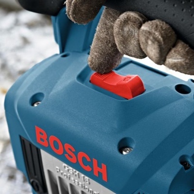 Ferramenta elétrica azul Bosch com botão vermelho segurada por luva