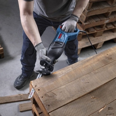 Pessoa a cortar madeira com serra tico-tico Bosch em oficina com paletes