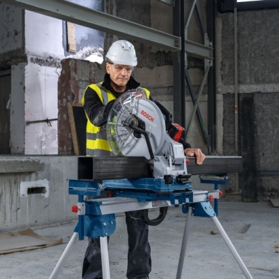 Serra de corte Bosch em ambiente industrial com trabalhador usando colete amarelo e capacete branco