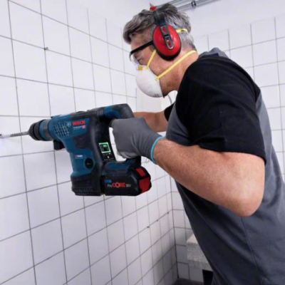 Homem usando furadeira Bosch a perfurar azulejos brancos