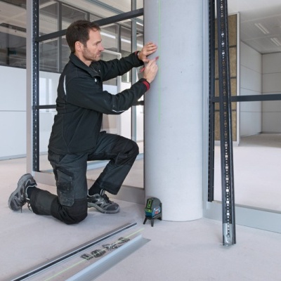 Homem com roupa preta a montar estrutura metálica cinza em espaço interno amplo