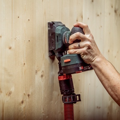 Lixadora elétrica a ser usada numa superfície de madeira clara