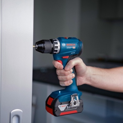 Parafusadora azul e preta Bosch a ser usada numa porta branca