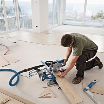 Homem a instalar pavimento em madeira clara com serra circular azul e branca
