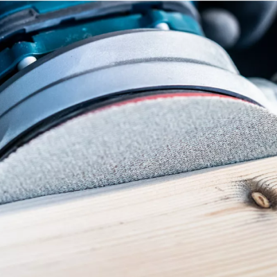 Lixadora elétrica a trabalhar numa tábua de madeira clara