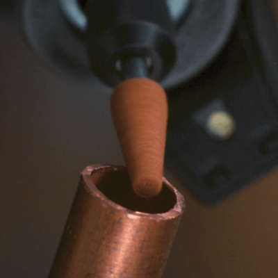 Ferramenta elétrica com ponta castanha inserida em tubo de cobre