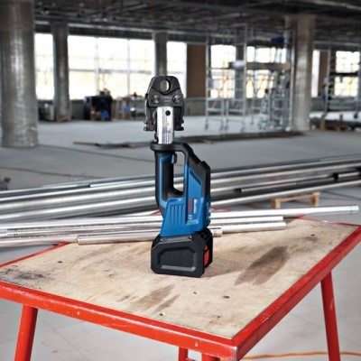 Ferramenta elétrica azul e preta numa mesa de madeira vermelha num local de construção