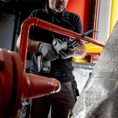 Pessoa a trabalhar com ferramenta elétrica em tubulação vermelha isolada