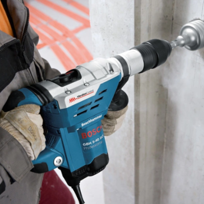 Furadeira elétrica Bosch azul e preta a ser usada numa parede branca